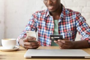 african american male marking purchase from iphone with credit card